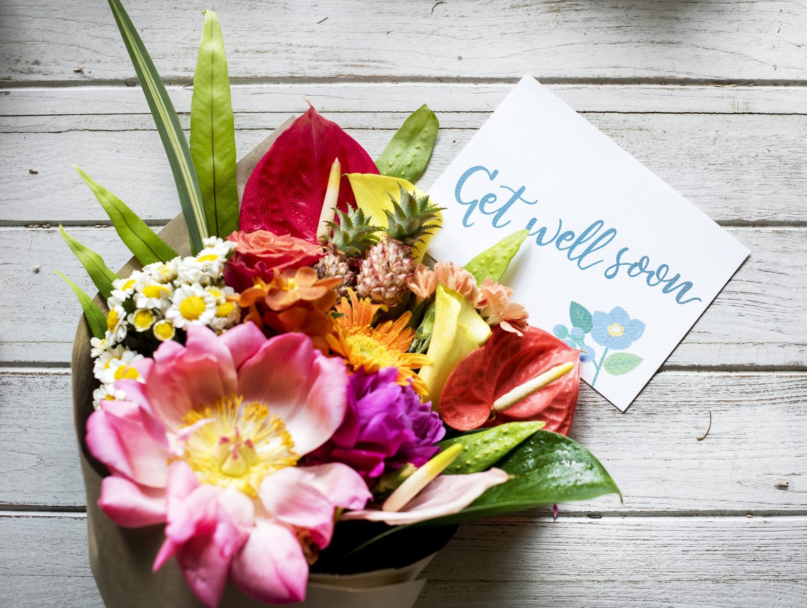 A bouquet of colorful flowers beside a card that reads Get well soon.